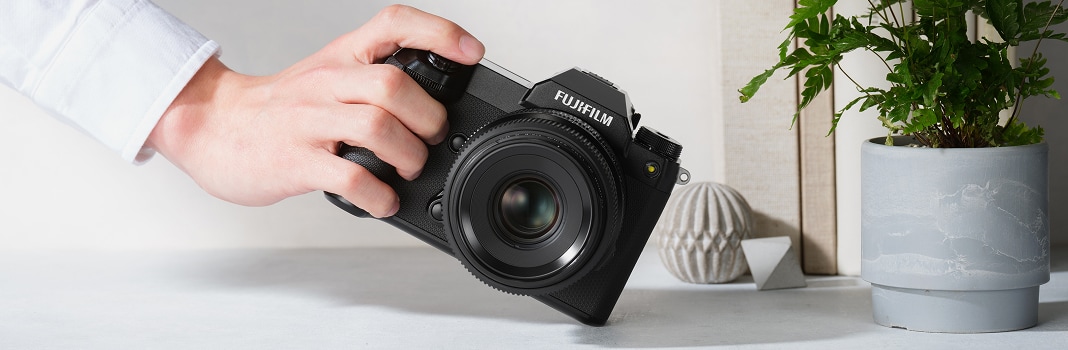 FUJIFILM GFX100S being held near a plant